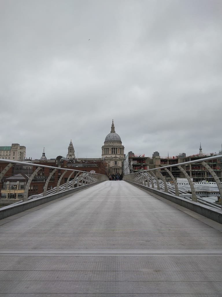 View of St. Paul's Cathedral and Millennium Bridge in London on an overcast day.