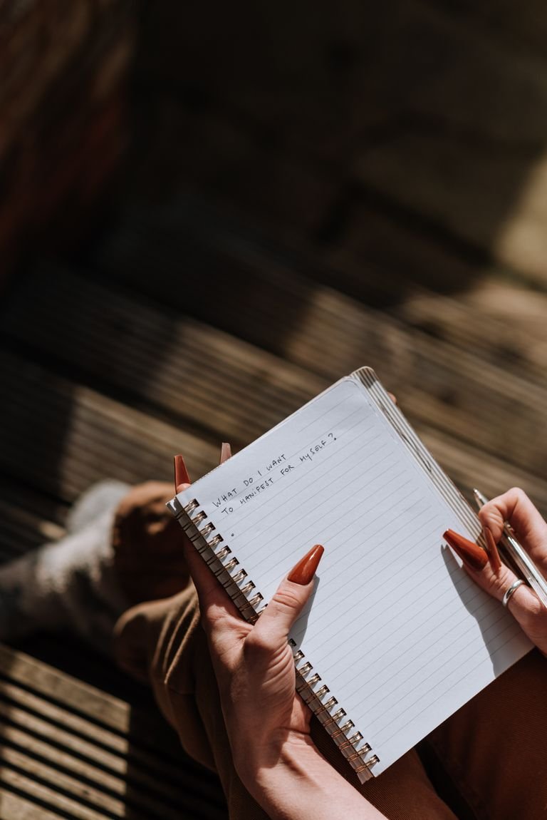 From above of crop anonymous female reading handwriting in notebook on blurred background in daytime