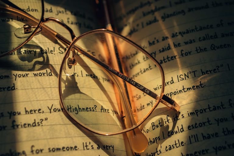 Vintage round spectacles rest on an open journal with handwritten notes.